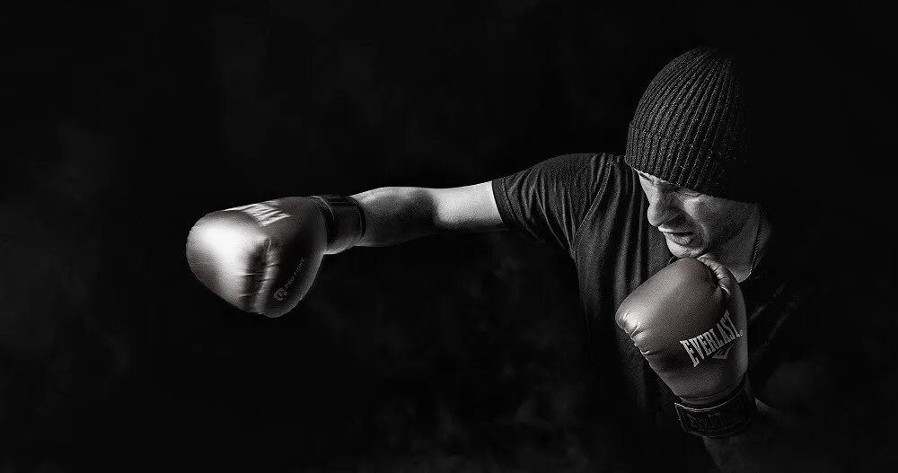黑白照中戴毛帽的拳擊手打出直拳，前手手臂完全伸直、肩膀往前推送，後手護在下巴旁